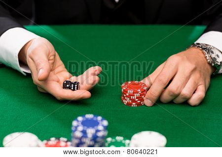 casino, gambling, poker, people and entertainment concept - close up of poker player with dice and chips at green casino table