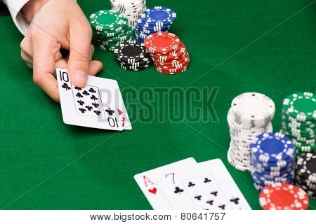 casino, gambling, poker, people and entertainment concept - close up of poker player with playing cards and chips at green casino table