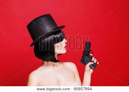 fashion beautifull model with pistol in hat, on red background