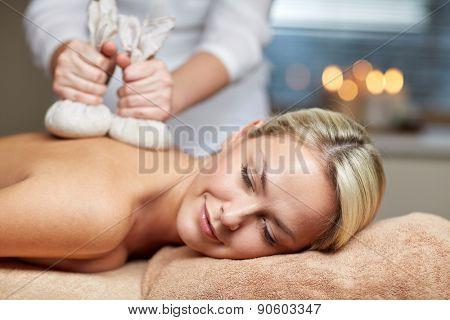 people, beauty, spa, healthy lifestyle and relaxation concept - close up of beautiful young woman lying and having herbal bag massage in spa