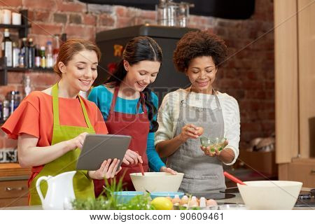 cooking class, friendship, food, technology and people concept - happy women with tablet pc computer in kitchen