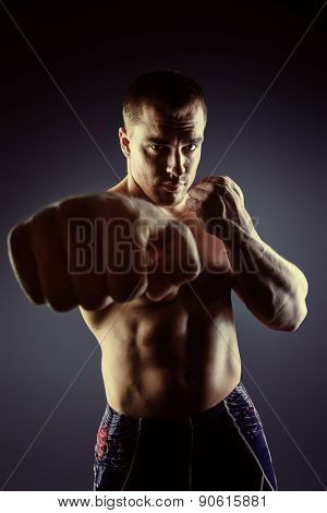 Strong muscular man fighting with fists. Martial arts. Fist fights, boxing. Bodybuilding. Black background.