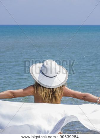 Woman in white sarong and straw hat at the  beach 
