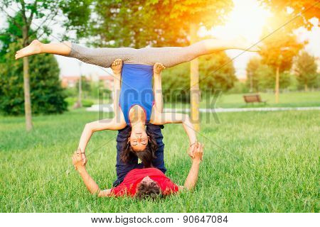 Couple Practicing Acroyoga In The Park