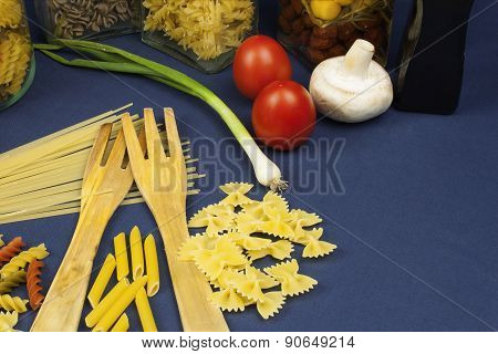 different kinds of pasta on the table, together with vegetables, ready for cooking