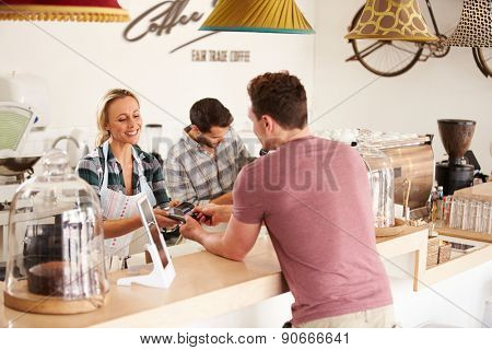 Young man paying for his order in a cafe