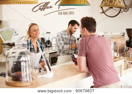 Young man paying for his order in a cafe