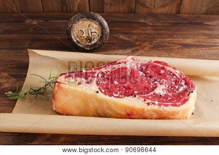 raw beef Rib bone  steak  on paper  and table with 2lb iron weight