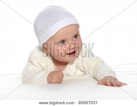 baby girl child lying down on white blanket smiling happy white clothing hat fashion portrait face studio shot isolated on white caucasian