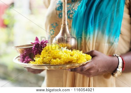 Indian girl with traditional plate of religious offerings and flowers for ear piercing ceremony. 