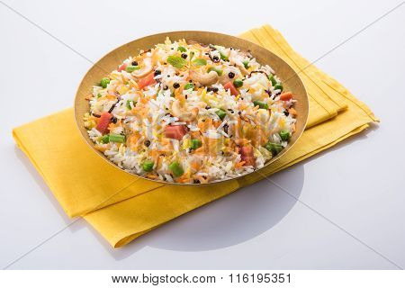 Veg biryani or veg pulav served in a round brass bowl over wooden background