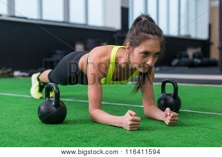 Fit woman doing plank exercise working on abdominal muscles in the gym