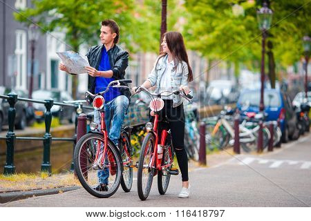Happy tourists sightseeing city with map on bikes