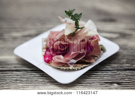 Fresh delicious Spanish tapas with hamon with fresh herbs and strawberries on the  wooden background . Great background for restaurant, cafe.