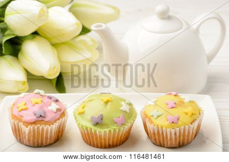 Muffins covered with icing sugar on white plate.