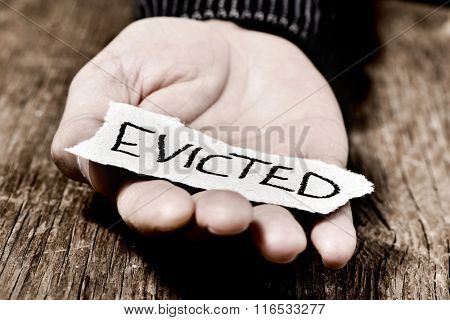 closeup of a piece of paper with the word evicted in the hand of a caucasian man