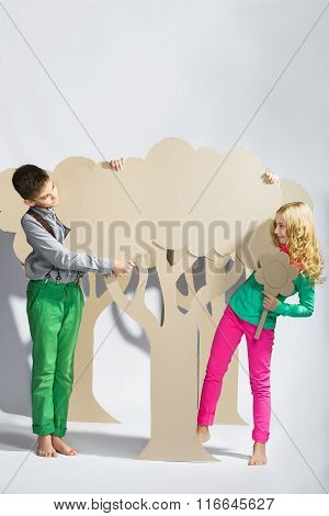 Love concept. Couple of kids. boy and girl hiding behind a cardboard tree