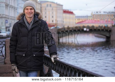 Mature man in winter clothes at the embankment of Moika river in St. Petersburg, Russia