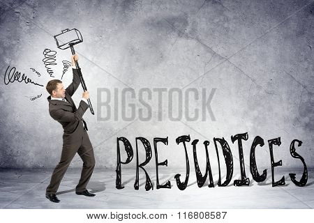 Businessman with hammer and word prejudices