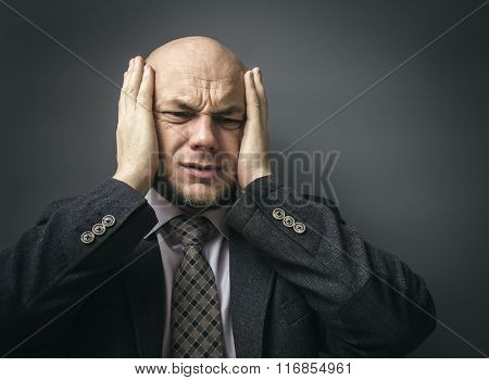 Portrait of an adult man in a business suit on a black background. Headache