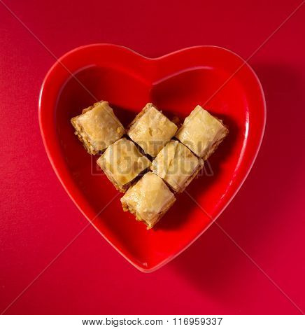 Popular middle eastern dessert - Paklawa in a red heart shaped dish. Unhealthy food concept. View from above.