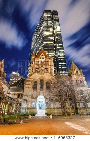 BOSTON, MASSACHUSETTS - APRIL 4, 2012: John Hancock Tower stands over Trinity Church. At 790 feet, it is the tallest building in the New England region.