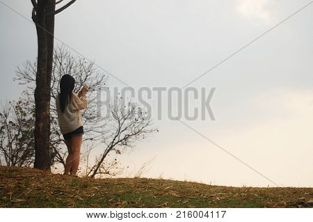Asian Thai Women Travelers Stand Alone Under Tree For Looking Sunset At Viewpoint On Top Of Mountain
