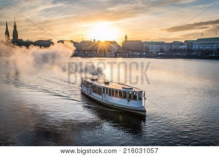 steamboat on Alster Lake in Hamburg Germany with cityscape in background during sunset