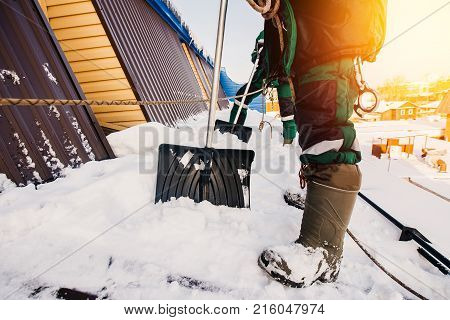Cleaning roofs of buildings from snow ice in the winter with a shovel.