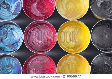 Top view of old CMYK paint cans on dark background. Colorful background.