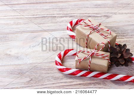 New Year's gift in a homemade box with a red bow near the and Christmas Candy canes.