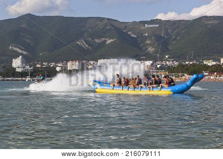 Gelendzhik, Krasnodar region, Russia - July 16, 2015: Horseback on an inflatable raft in Gelendzhik Bay. Driver of motorcycle aqueous drenches water attraction participants. Beach resort Gelendzhik, Krasnodar region, Russia