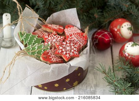Gingerbread In A Tin Box In The Background With Christmas Toys, A Candle And Fir Branches.