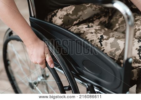 Woman veteran in wheelchair returned from army. Close-up photo veteran woman in a wheelchair. Wheelchairs and legs in military uniform.