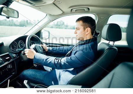 Attractive handsome elegant man in a business suit driving an expensive car
