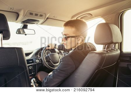 Young cut businessman wearing suite driving car