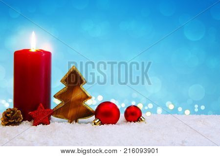 Avent candle and christmas decoration isolated on blue background. Christmas background with snow, candle and wood fir tree.