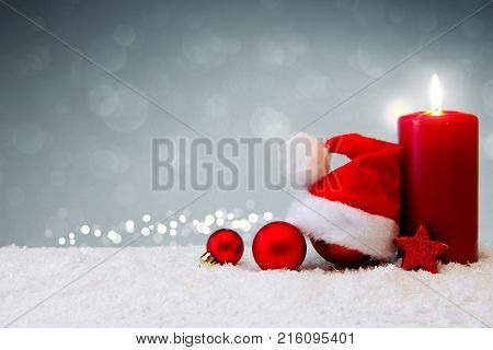Avent candle and christmas decoration isolated on gray background. Christmas background with snow, candle and Santa Claus hat.