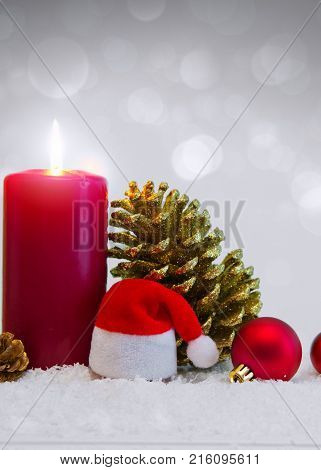 Avent candle and christmas decoration isolated on gray background. Christmas background with snow, candle and Santa Claus hat.