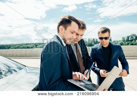 three Businessman Using Digital Tablet Outside against car.