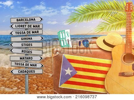 Concept of summer traveling with old suitcase and Catalonia town sign with burning sun