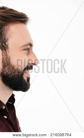 Side view half face portrait of a smiling bearded man laughing and looking away at copy space isolated over white background