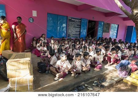 PONDICHERY PUDUCHERY INDIA - SEPTEMBER 04 2017. Outdoor meeting of the children of the school with uniforms sitting on the floor waiting for sport equipments as a gift from an association.