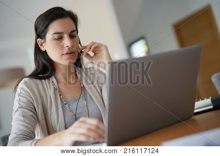 Home-office teleoperator talking on phone with headset