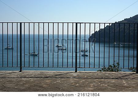 Yachts moored in a bay of Palmaria Island seen behind a railing