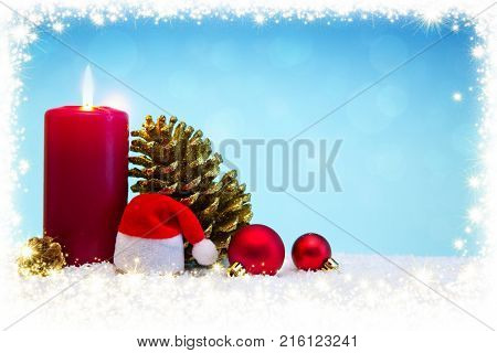 Avent candle and christmas decoration isolated on blue background. Christmas background with snow, candle and Santa Claus hat.