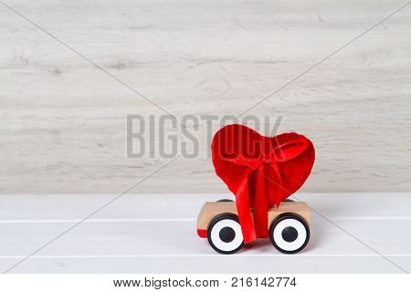 wooden toy car with red heart on grey background