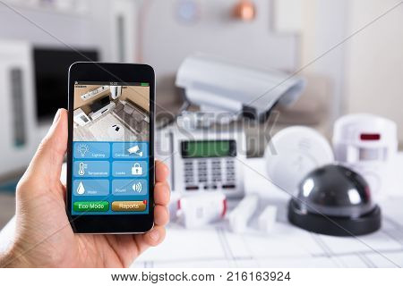 Close-up Of A Person's Hand Holding Mobile Phone With CCTV Camera Footage On Screen