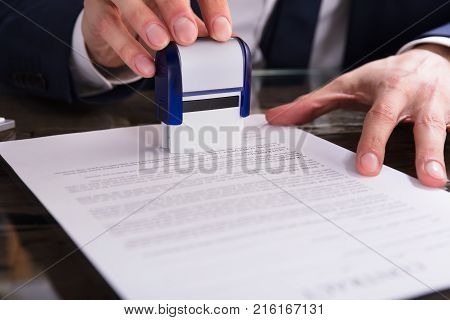 Close-up Of A Businessperson's Hand Stamping Document In Office