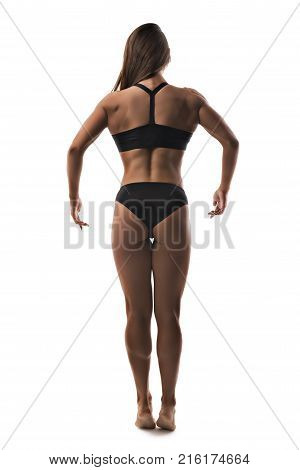 Muscular female bodybuilder wearing black top and pants with her dark long hair loose full length isolated rearview on white background